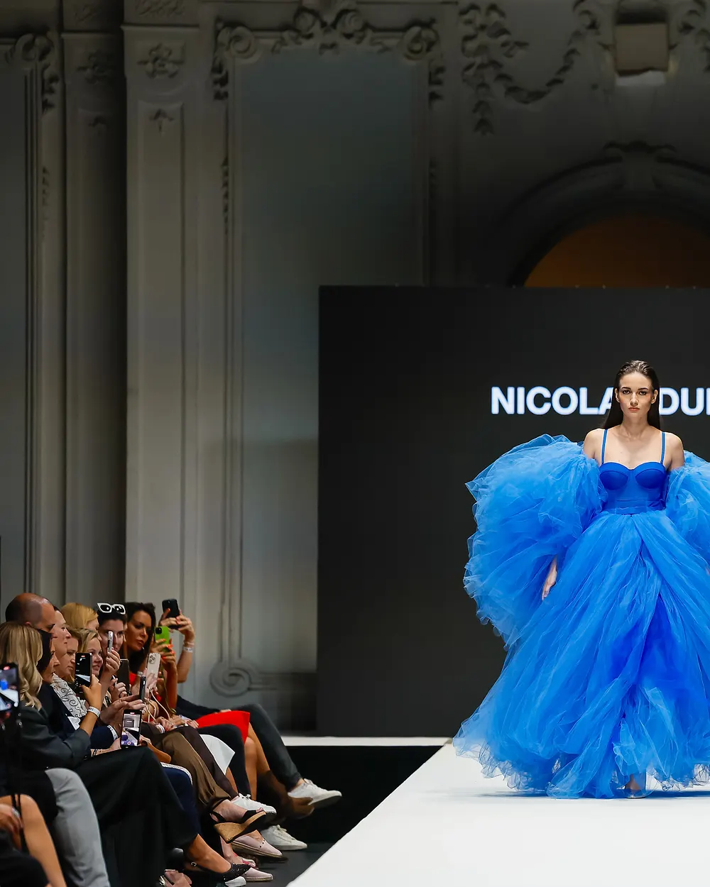 Model in einer voluminösen blauen Tüllrobe auf dem Laufsteg