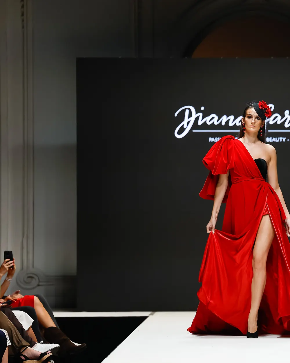 Model in einer roten Robe mit hoher Beinschlitzung vor dunklem Hintergrund