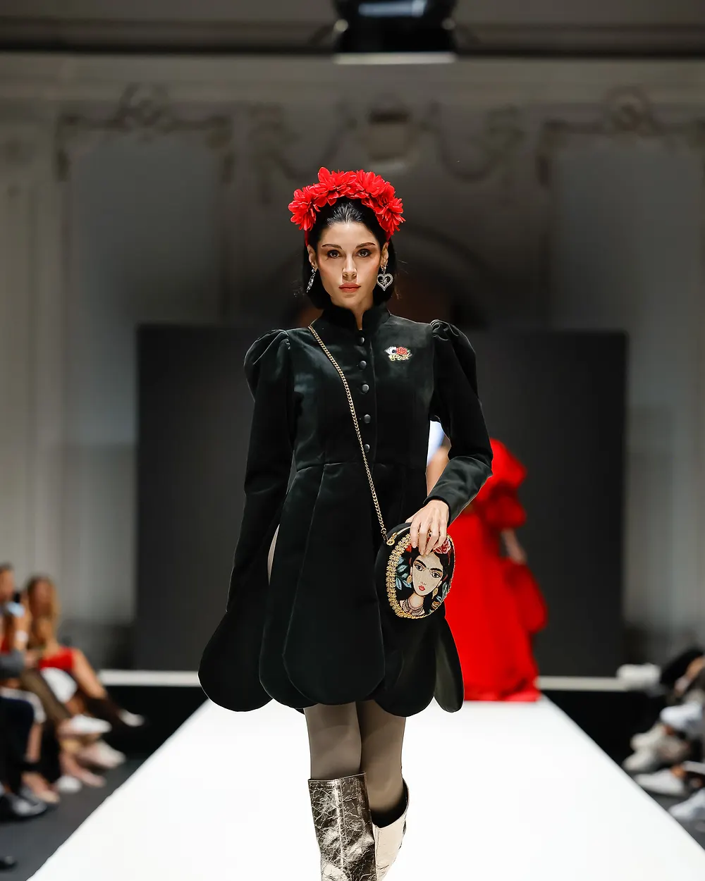 Model in schwarzem Samtmantel mit rotem Blumenkranz im Haar