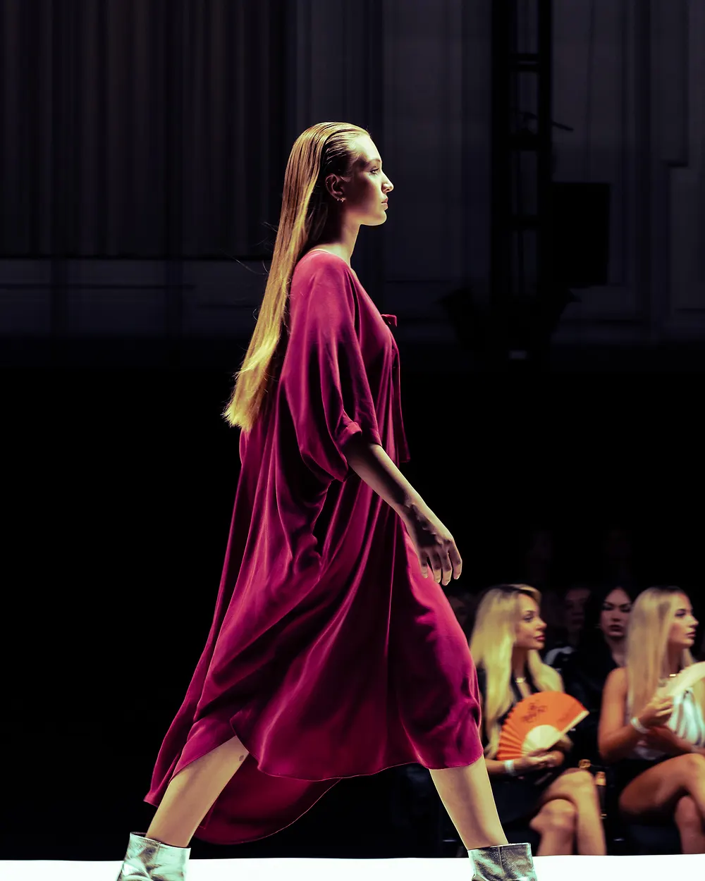 Model in einem weiten magentafarbenen Kleid auf dem Laufsteg