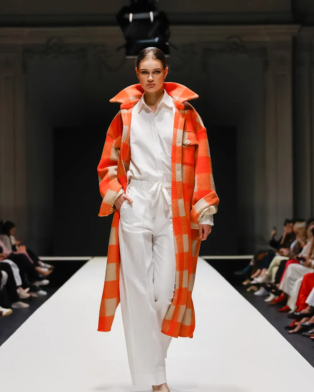 Model in weißem Anzug unter einem orange karierten Mantel